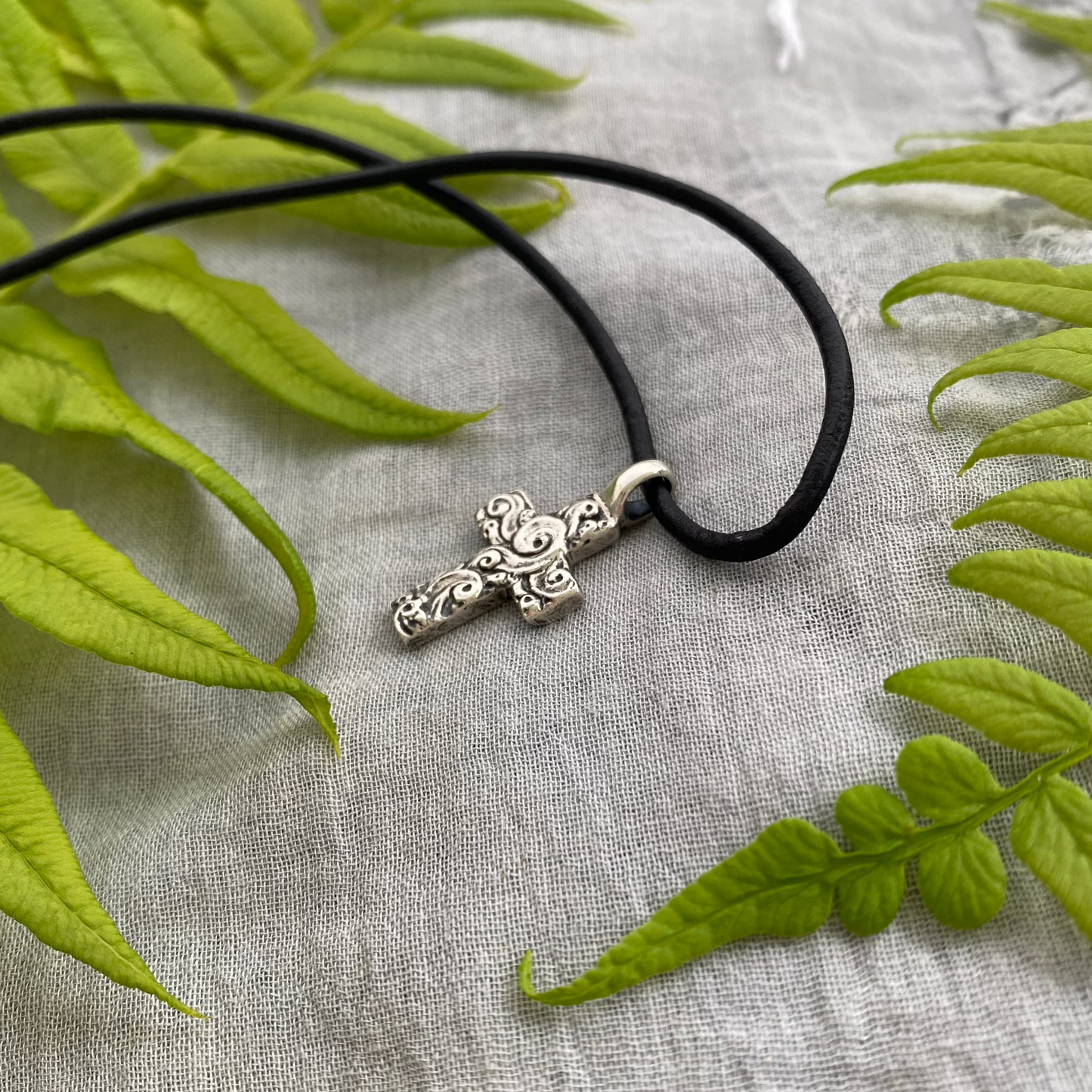 chunky small sterling silver cross on black leather cord with unique swirling wave design, gift for men and women, handcarved and produced in USA