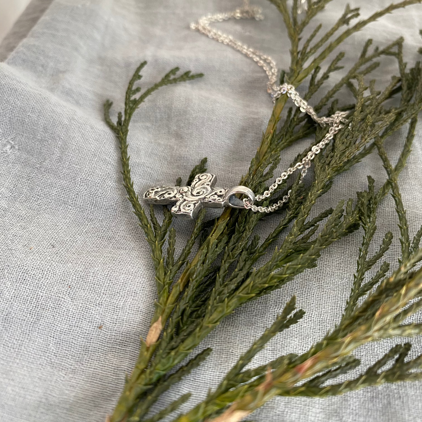 Chunky sterling silver cross necklace with swirling wave design on sterling silver chain