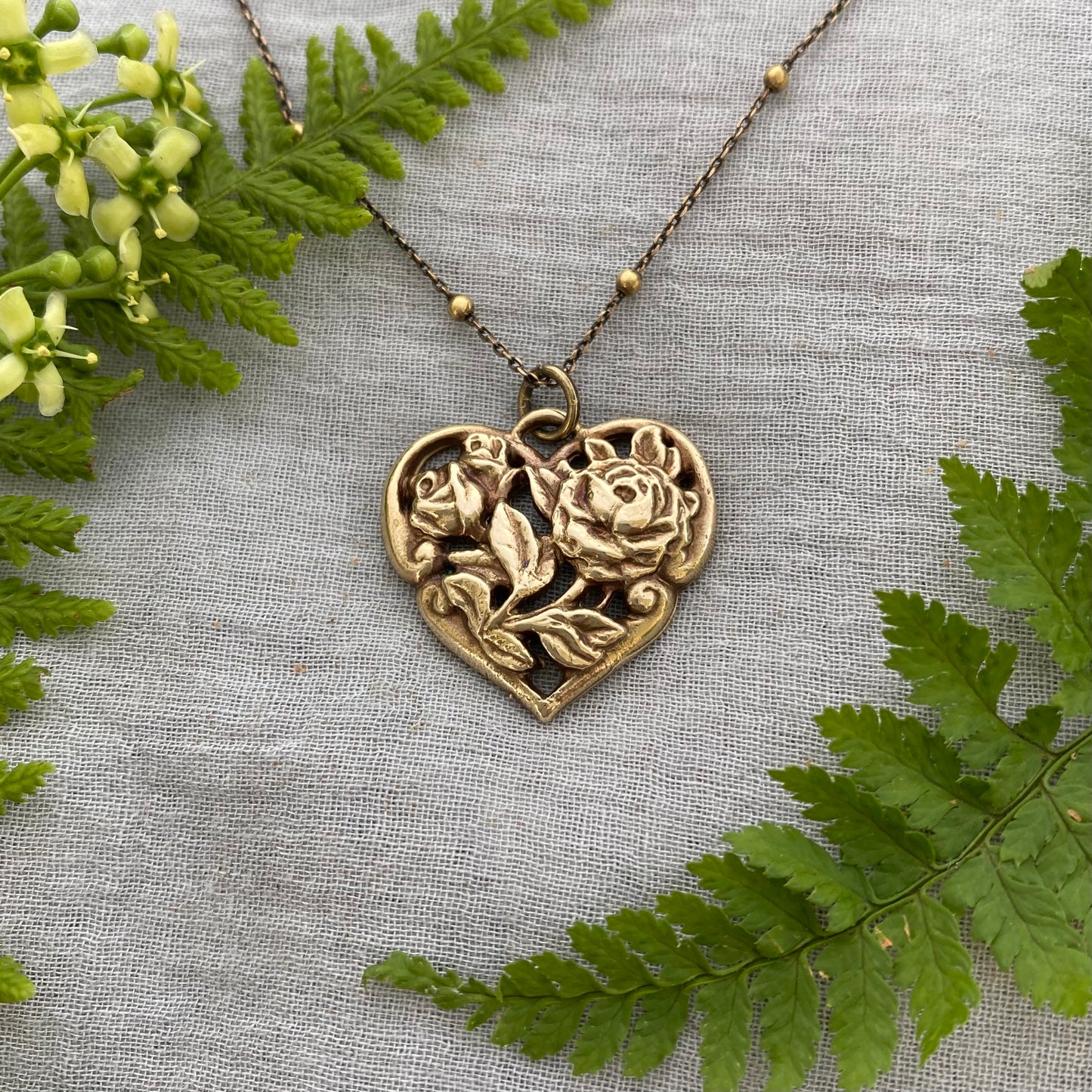 Richly carved Victorian-style brass heart necklace with roses on antiqued brass satellite cable chain