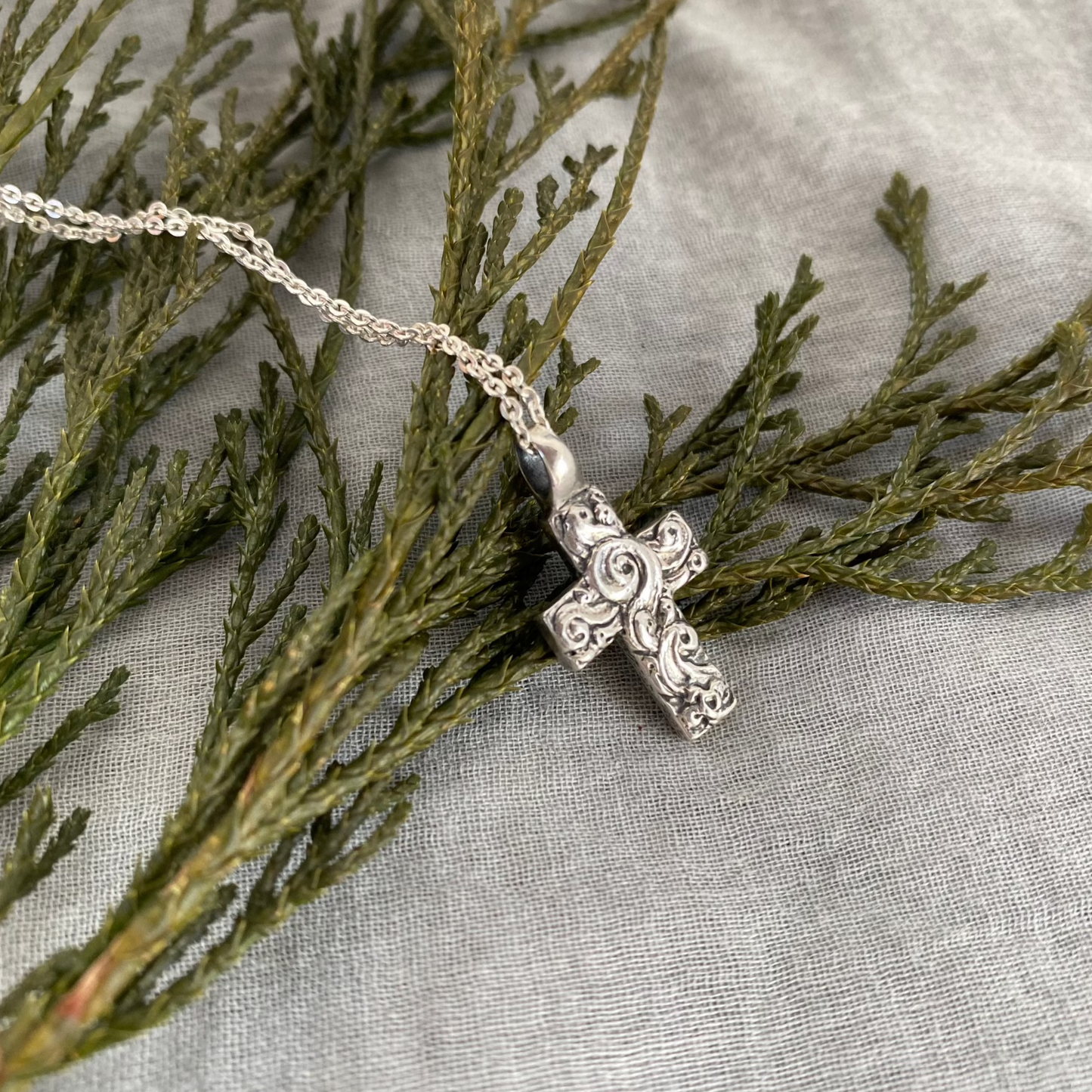 Chunky sterling silver cross necklace with swirling wave design on sterling silver chain