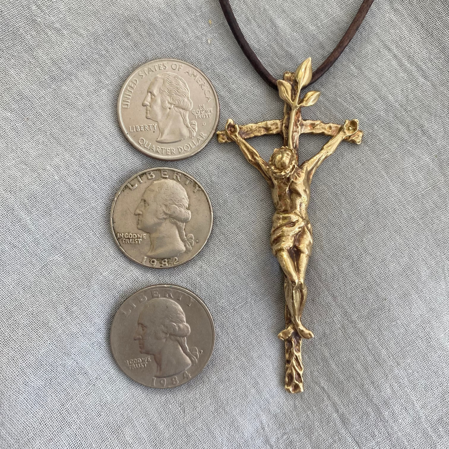 Large brass crucifix necklace; brown leather cord; realistic hand carved corpus; Jesus' suffering, death; leaves symbolizing new life