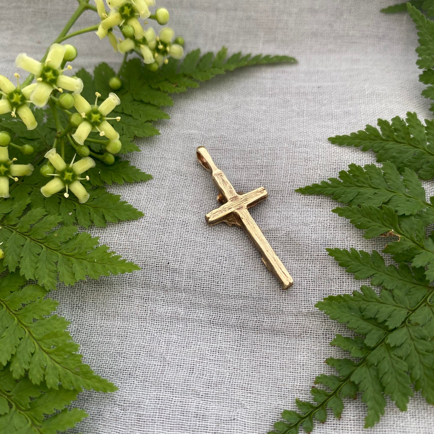 Dainty floral cross pendant for a necklace; gold toned brass; forget-me-not blossoms, leaves, wood grain texture; feminine flower; no chain