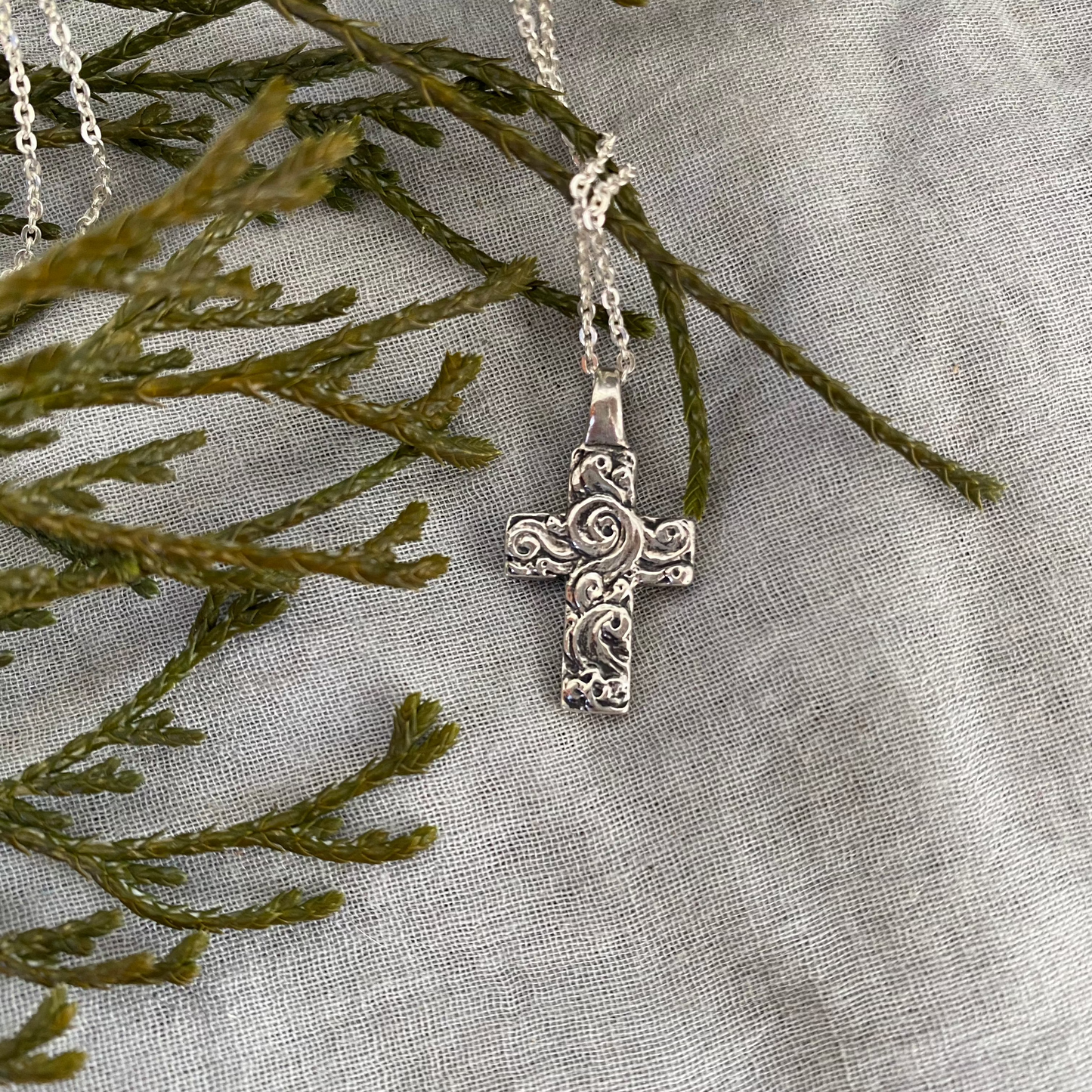 Chunky sterling silver cross necklace with swirling wave design on sterling silver chain