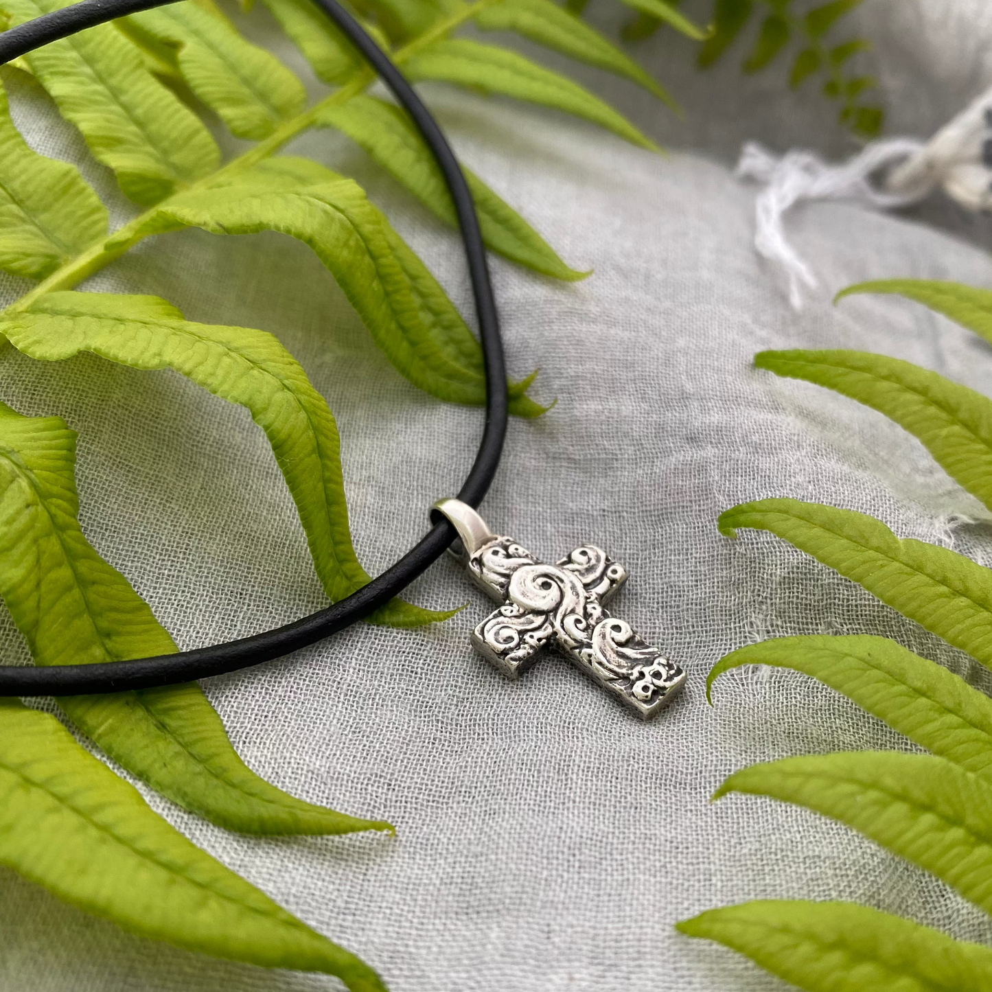 chunky small sterling silver cross on black leather cord with unique swirling wave design, gift for men and women, handcarved and produced in USA