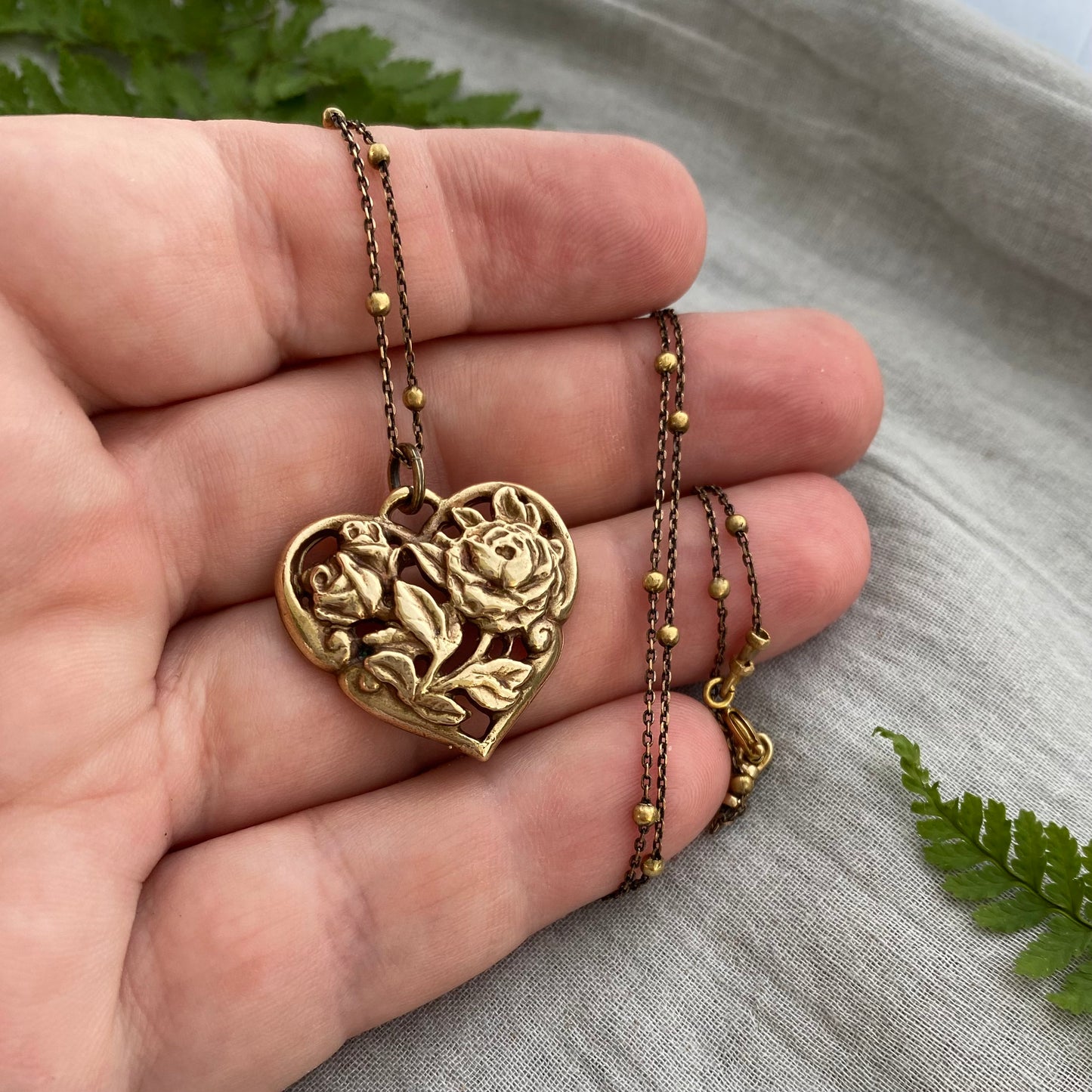 Richly carved Victorian-style brass heart necklace with roses on antiqued brass satellite cable chain