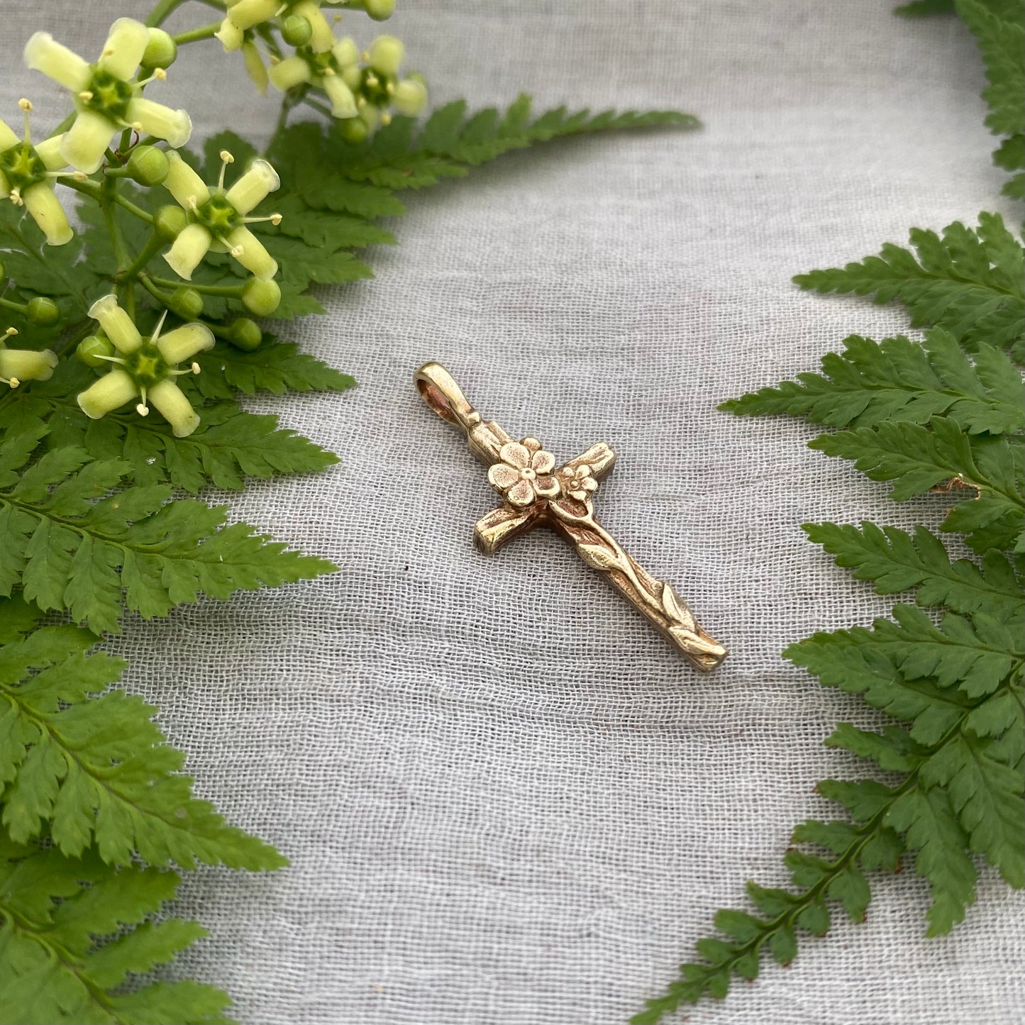 Dainty floral cross pendant for a necklace; gold toned brass; forget-me-not blossoms, leaves, wood grain texture; feminine flower; no chain