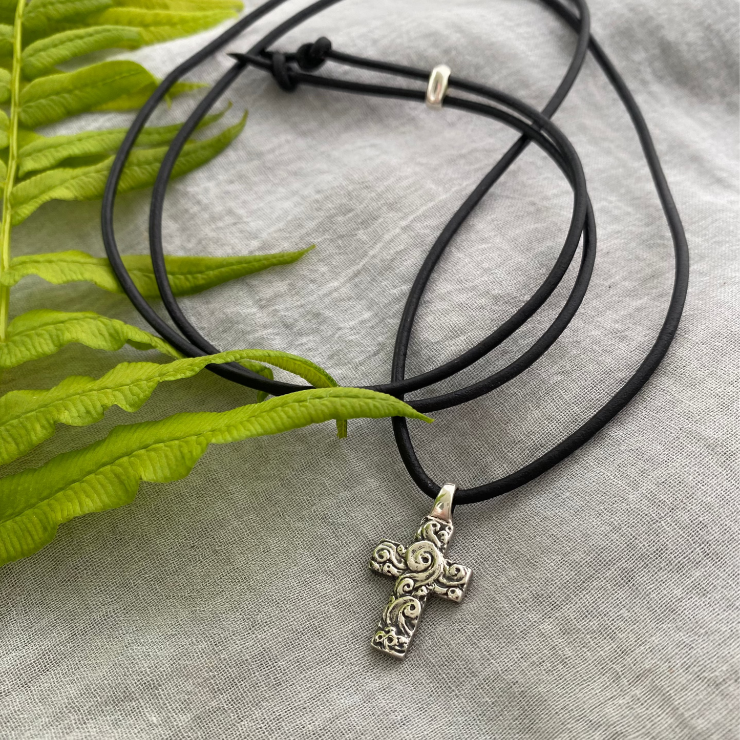 chunky small sterling silver cross on black leather cord with unique swirling wave design, gift for men and women, handcarved and produced in USA