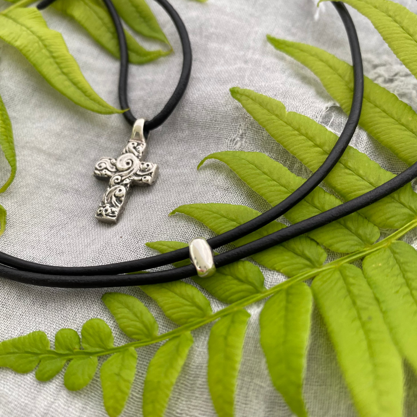 chunky small sterling silver cross on black leather cord with unique swirling wave design, gift for men and women, handcarved and produced in USA