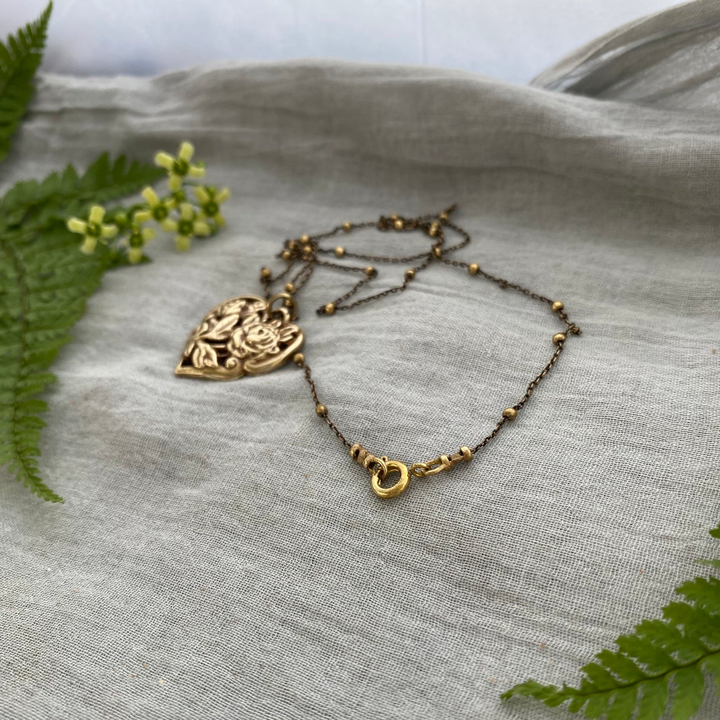 Richly carved Victorian-style brass heart necklace with roses on antiqued brass satellite cable chain