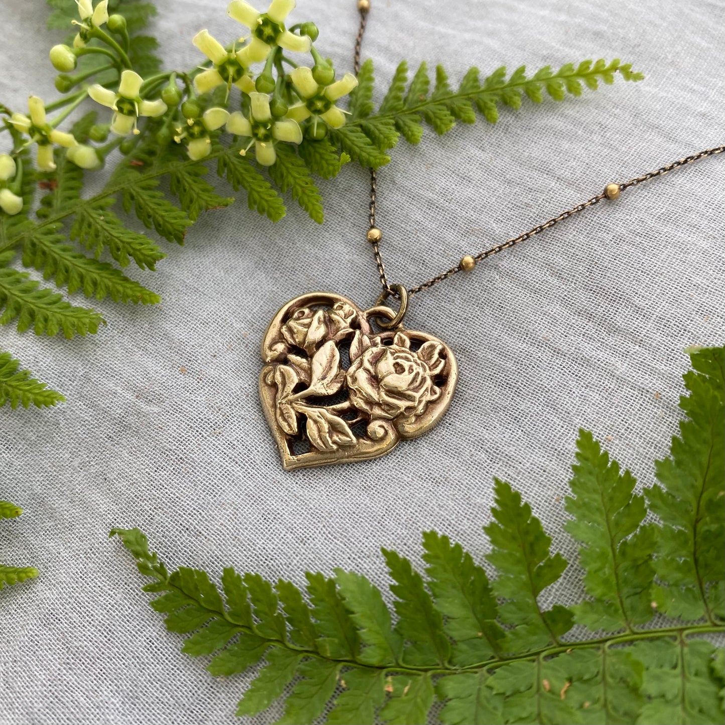 Richly carved Victorian-style brass heart necklace with roses on antiqued brass satellite cable chain