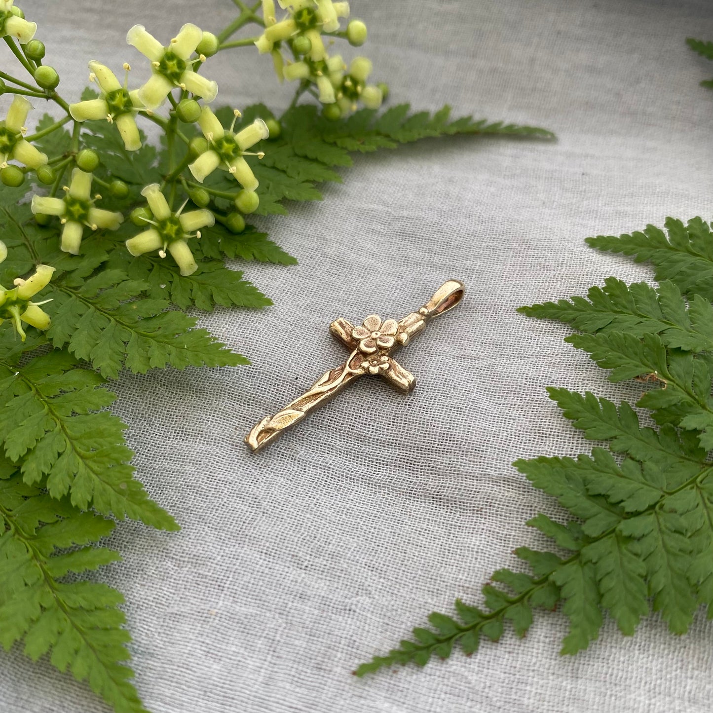 Dainty floral cross pendant for a necklace; gold toned brass; forget-me-not blossoms, leaves, wood grain texture; feminine flower; no chain
