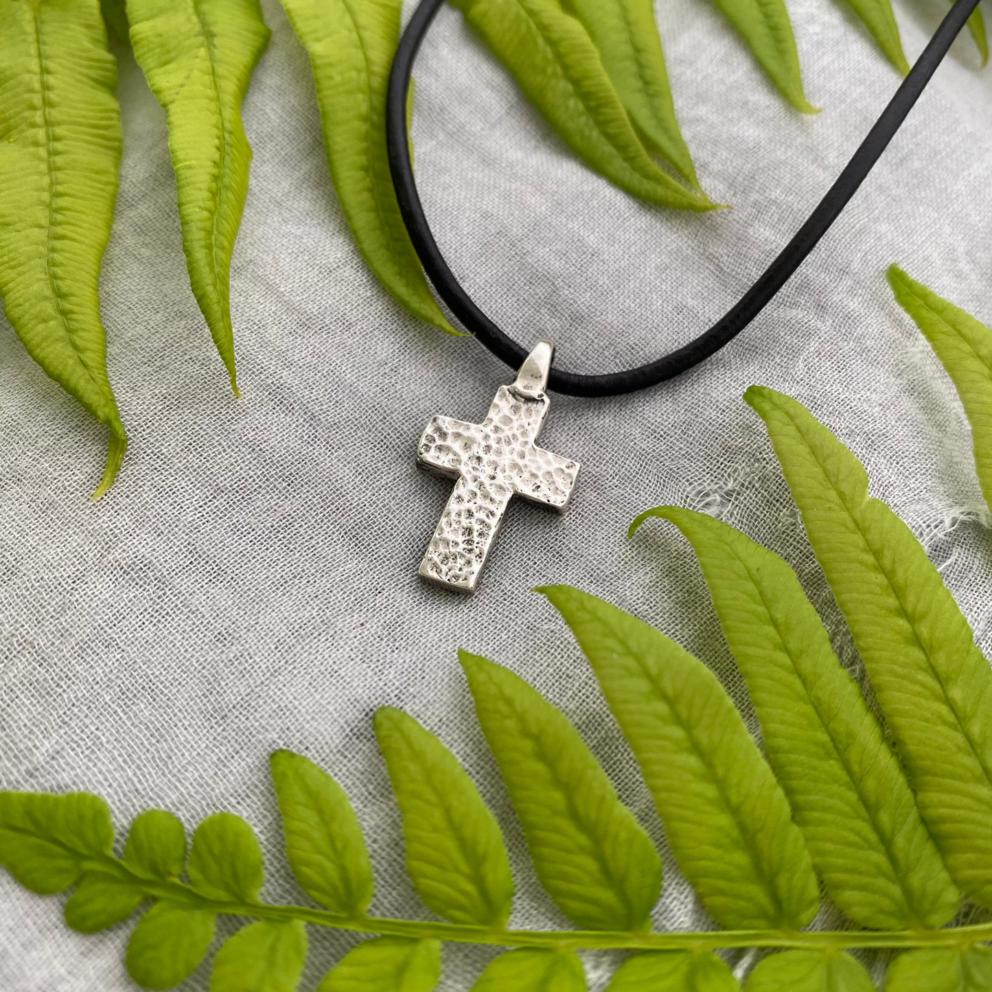 chunky small sterling silver cross on black leather cord with unique swirling wave design, gift for men and women, handcarved and produced in USA