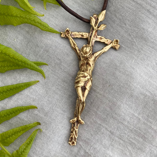Large brass crucifix necklace; brown leather cord; realistic hand carved corpus; Jesus' suffering, death; leaves symbolizing new life