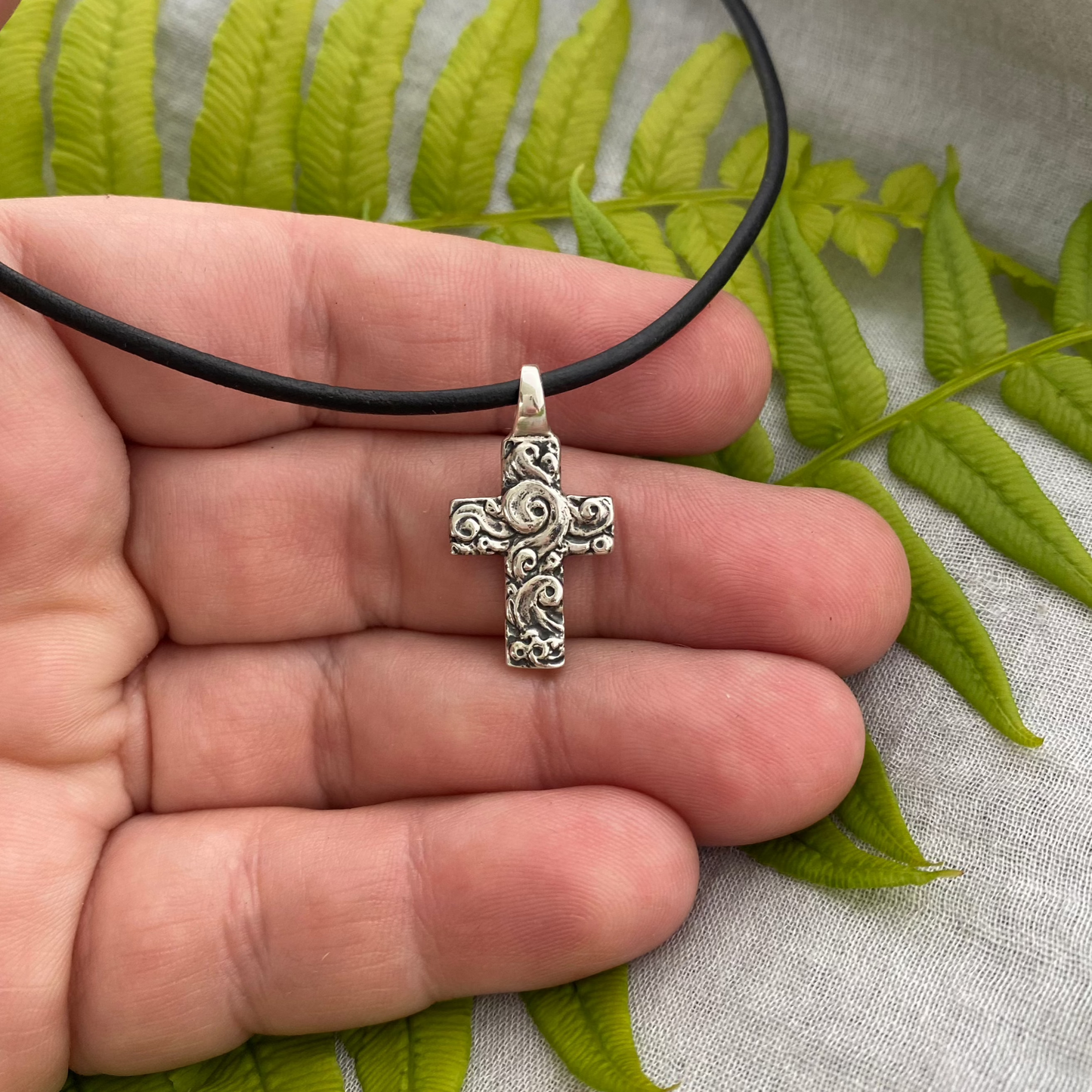chunky small sterling silver cross on black leather cord with unique swirling wave design, gift for men and women, handcarved and produced in USA