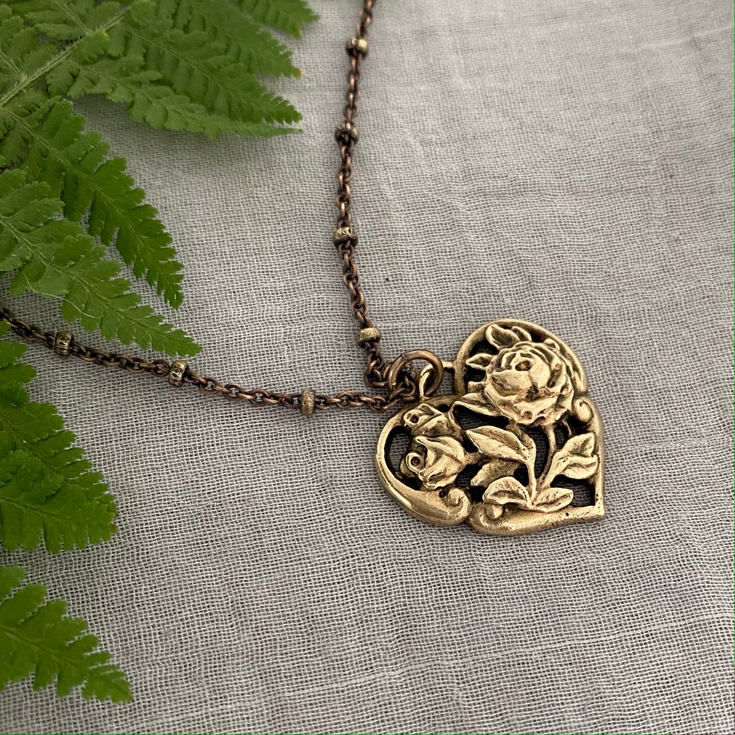 Brass floral heart necklace on satellite chain