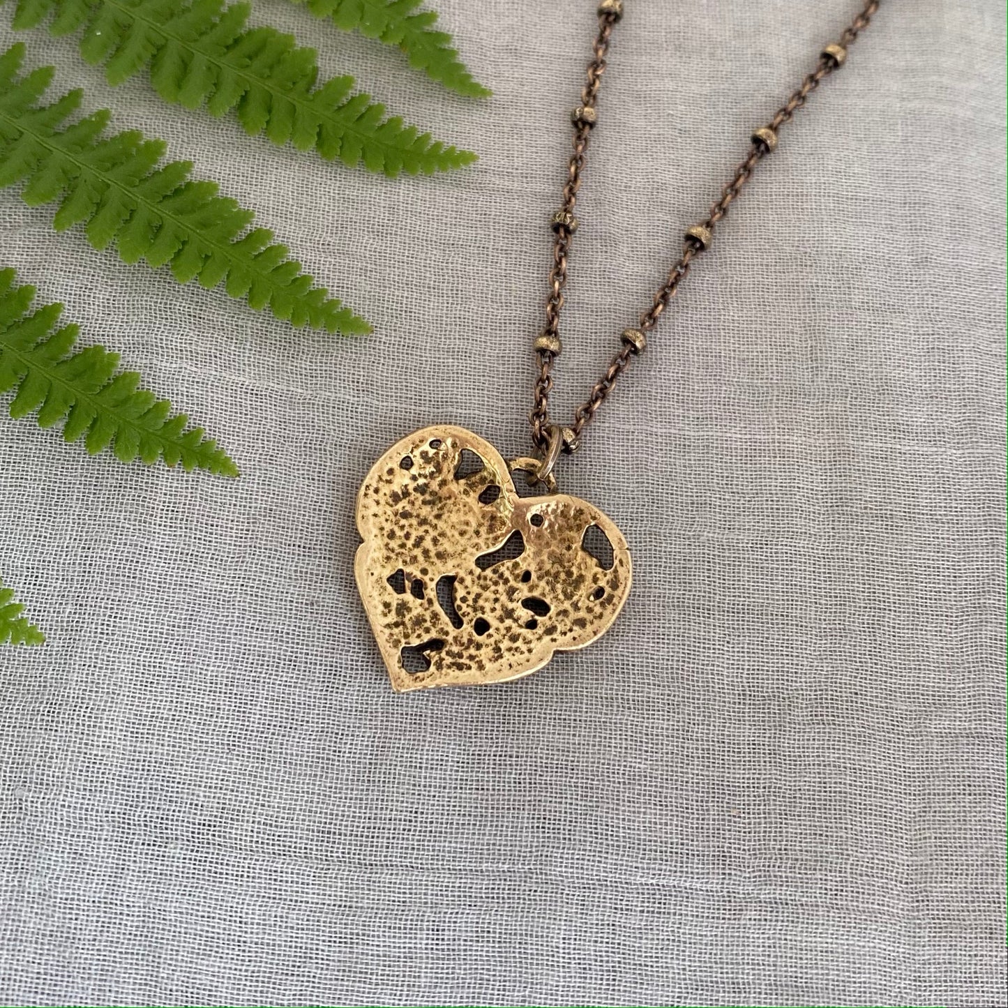 Brass floral heart necklace on satellite chain