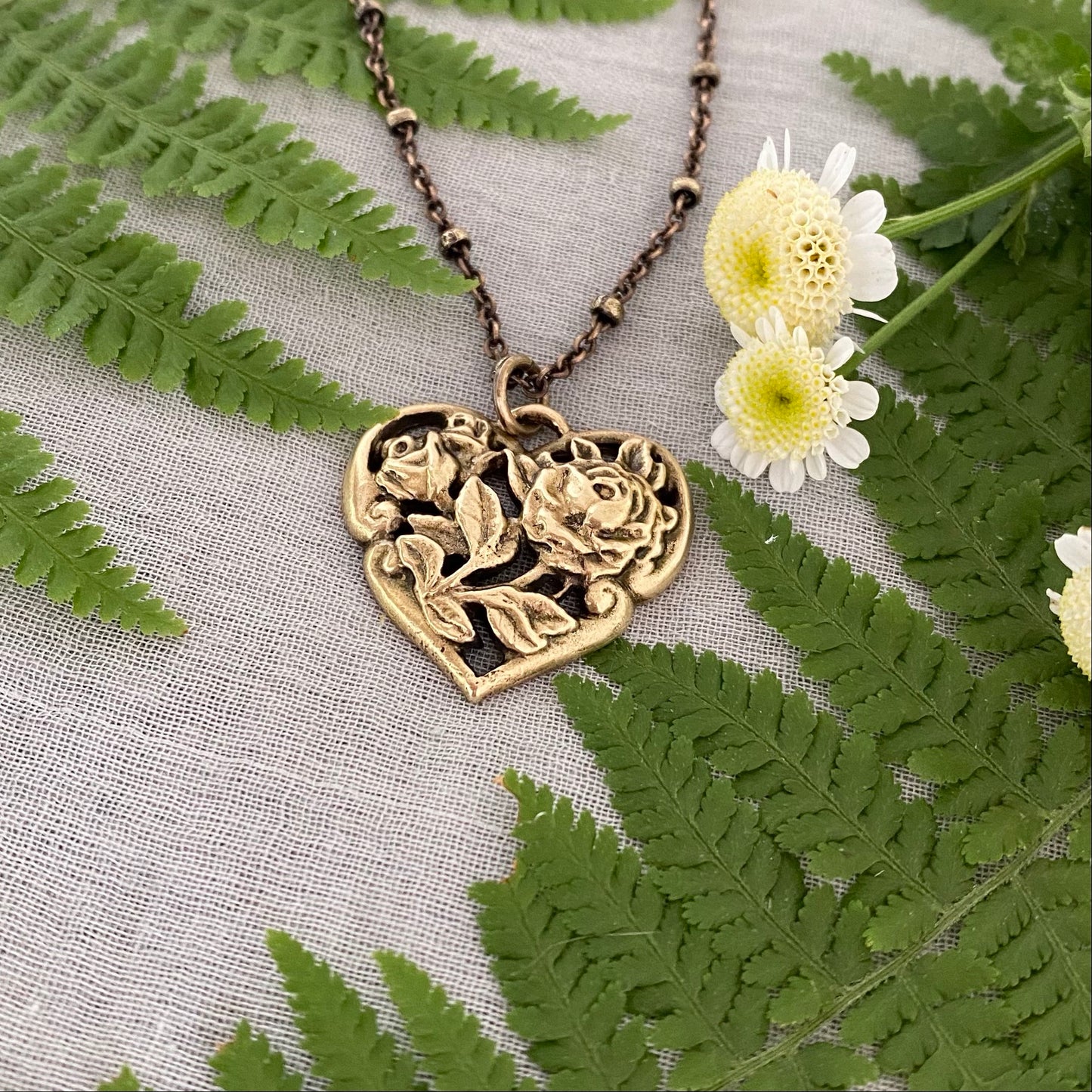 Brass floral heart necklace on satellite chain